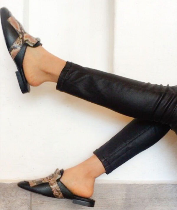 Zapatos tipo zuecos femeninos, de piel color negro, con detalle de “barbas” enfrente imitación animal print de serpiente que cubre todo el frente del zapato. Encima de esta pieza lleva una tira negra que pasa por lo ancho. Zapatos cómodos, sin tacón alto.