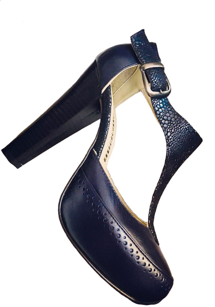 Zapatos tipo T-strap de cuero color azul marino con 2 tipos de texturas. Tacón alto y ancho. Con una hebilla color oro viejo.